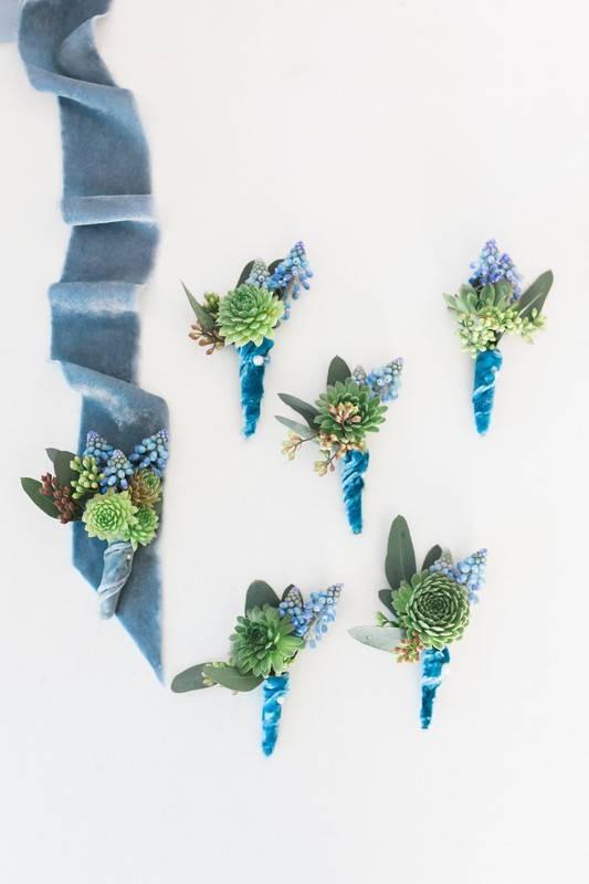 collection of succulent wedding boutonnieres with stems wrapped in teal velvet ribbon