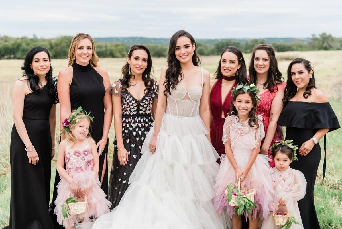 Bride posing with wedding party wearing black and pink dresses