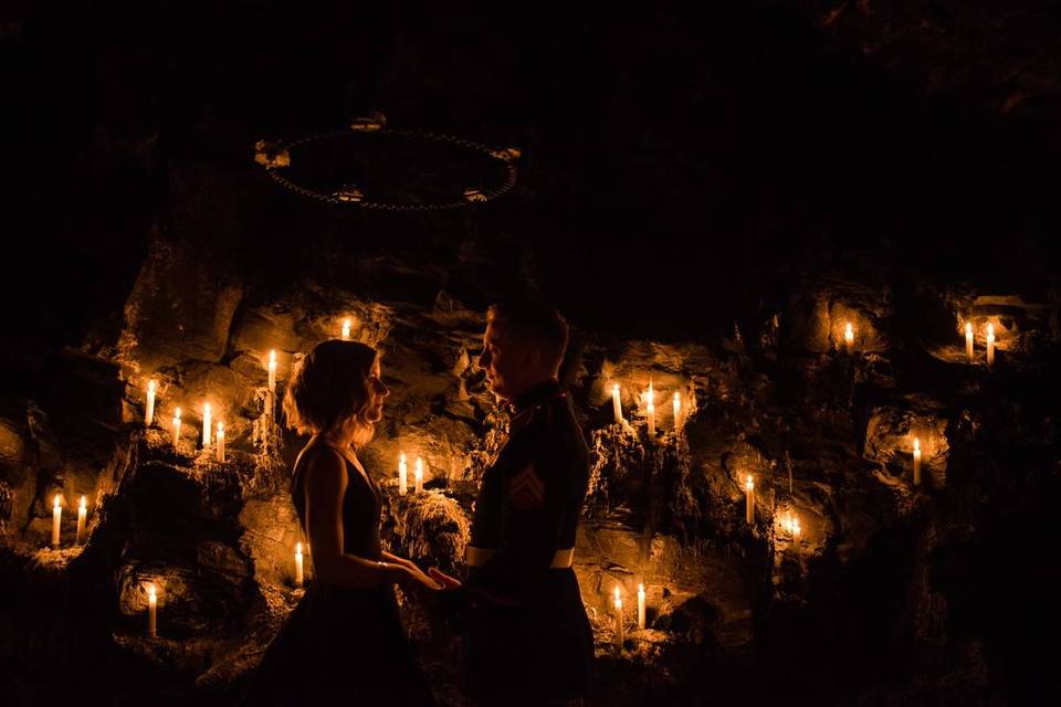 bride and groom standing in dark room surrounded by candles