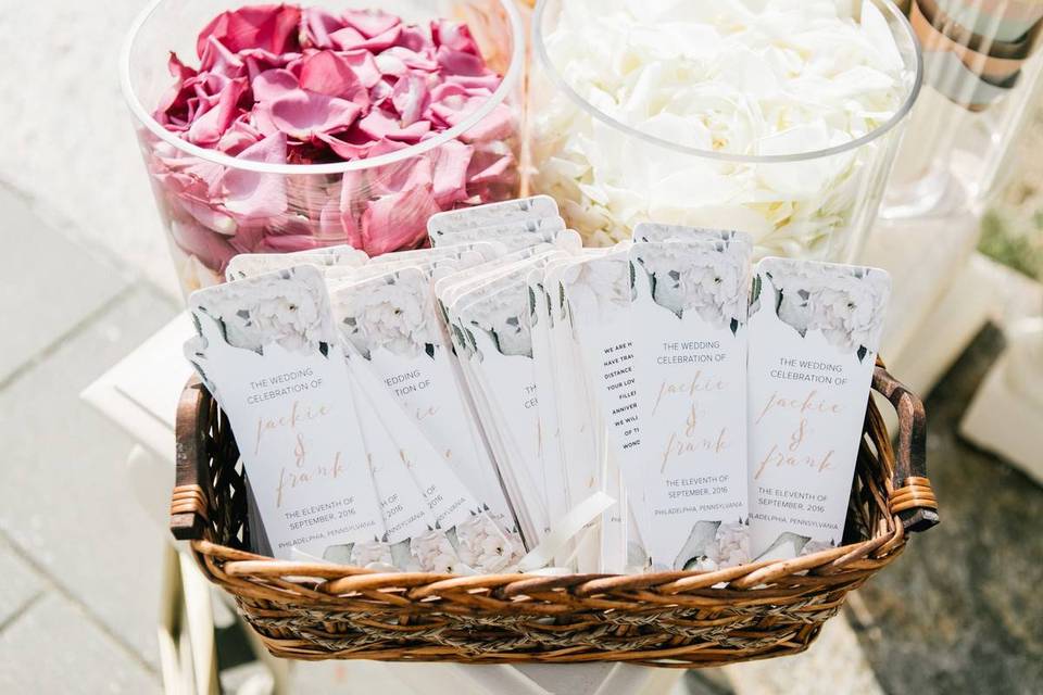 wedding ceremony programs with white and blush pink floral print in woven basket on table