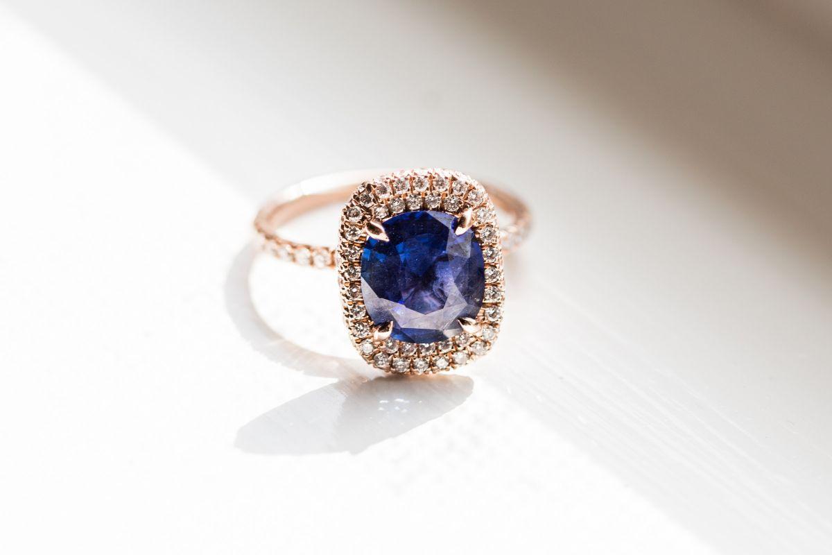 cushion-cut blue engagement ring with yellow gold double halo setting and thin pave band