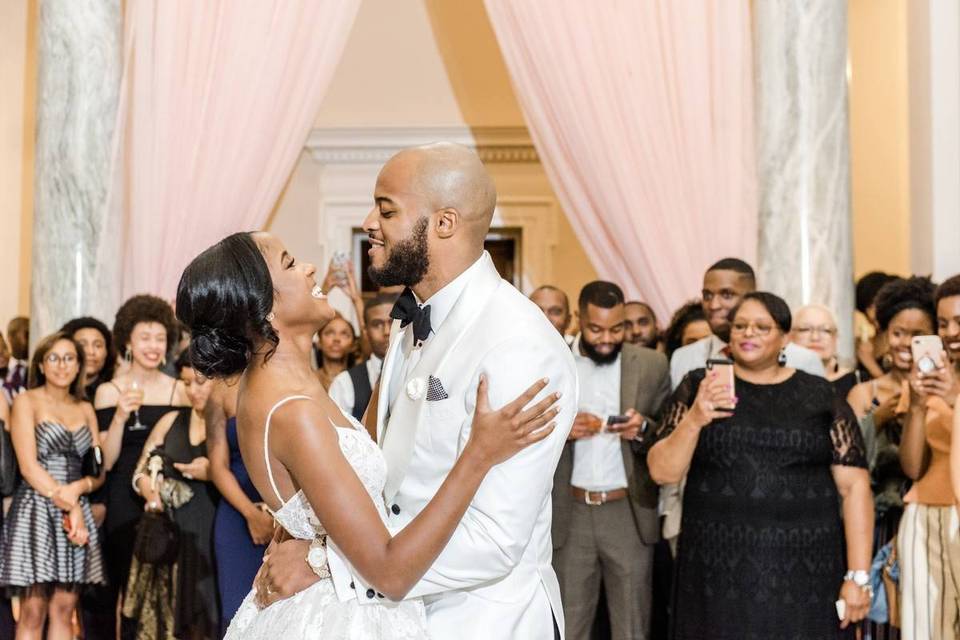 couple during first dance while guests watch from the side of the room