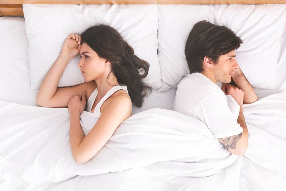 couple in white bed facing opposite directions