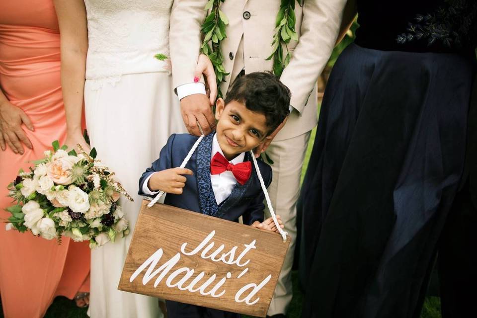 close up of ring bearer posing with wedding party and holding 