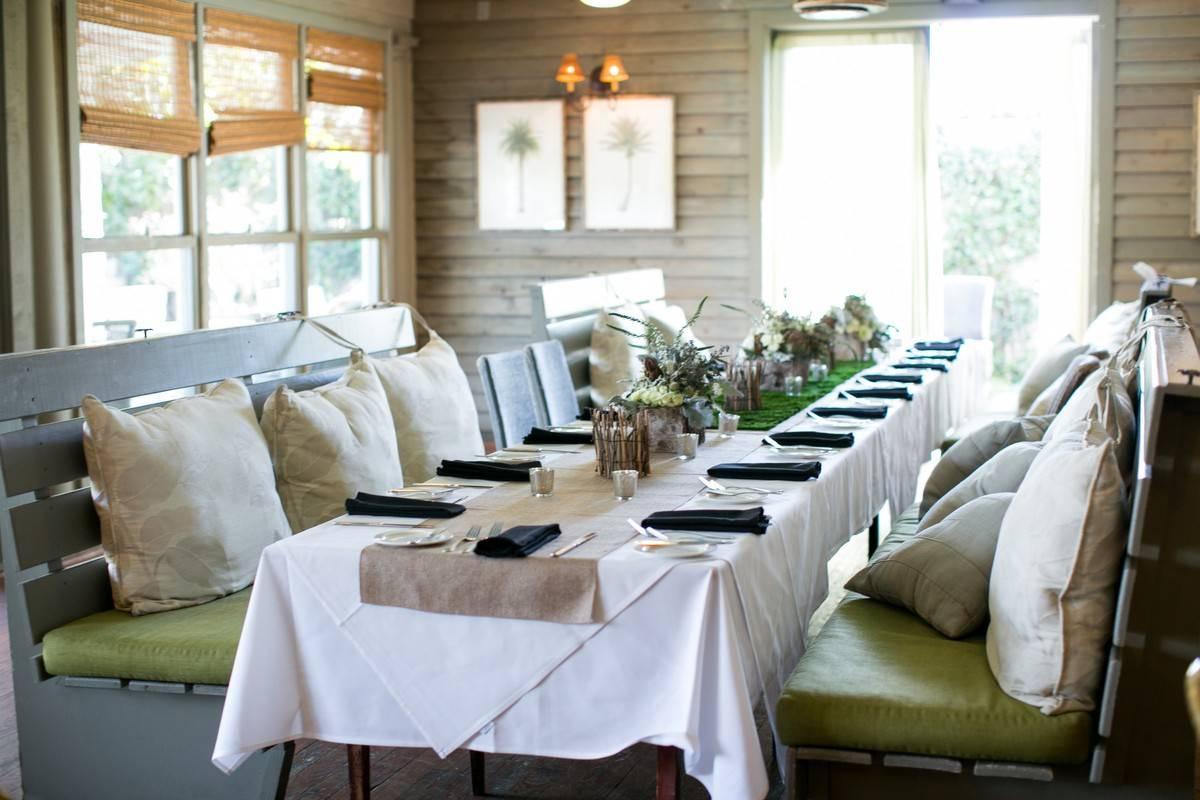 intimate wedding reception table with bench seating, throw pillows, and small floral centerpieces