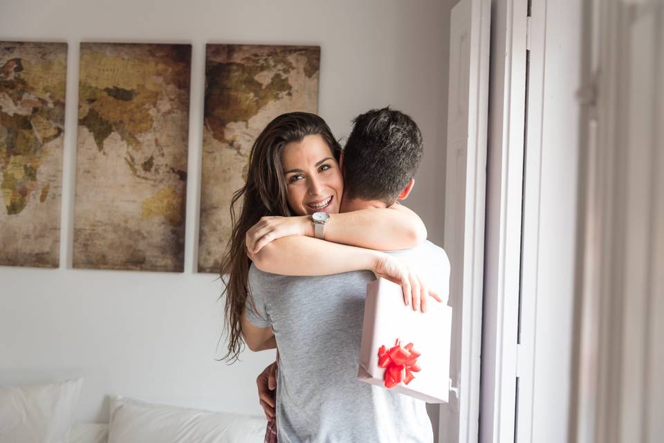 woman hugging a man and holding a gift with a red bow