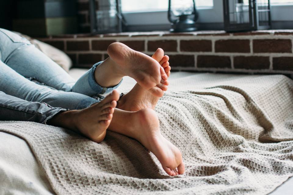 two pairs of feet tangled on a bed