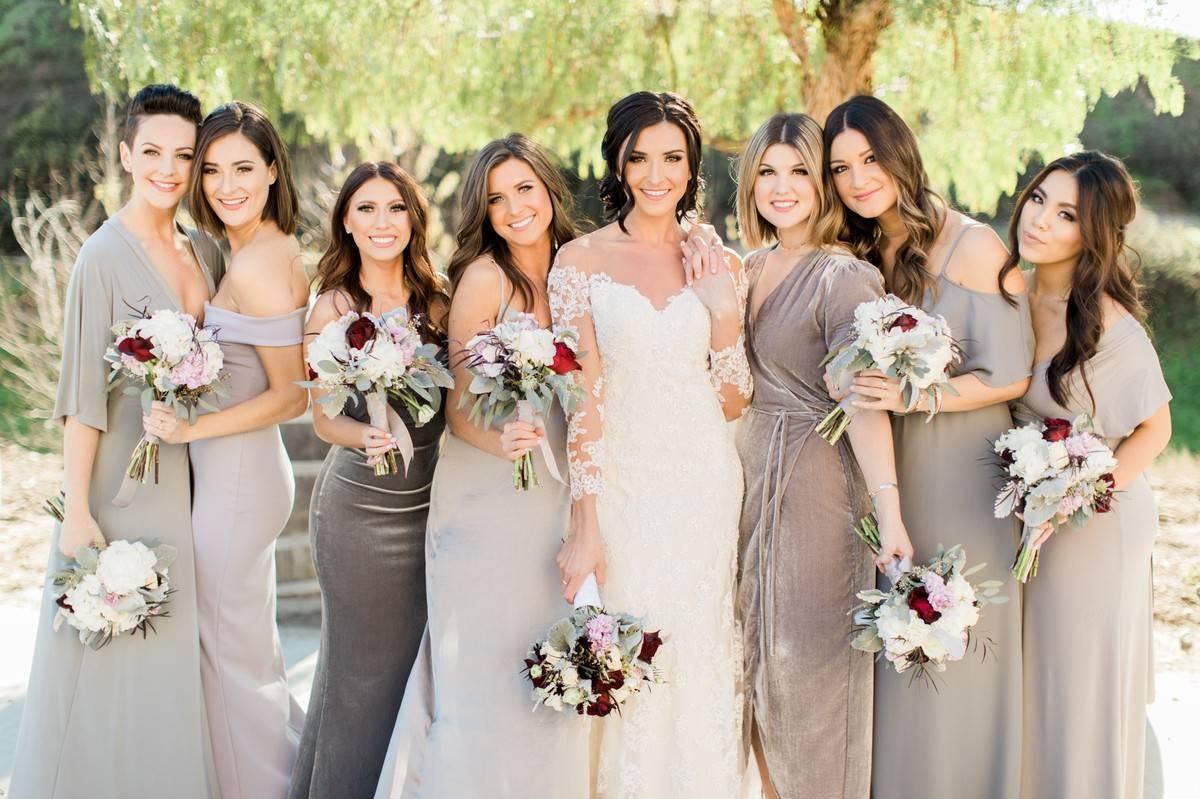 Bride posing with bridesmaids in varying shades of gray dresses