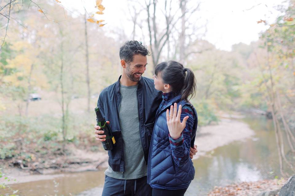 Couple showing off engagement ring and holding champagne after getting engaged