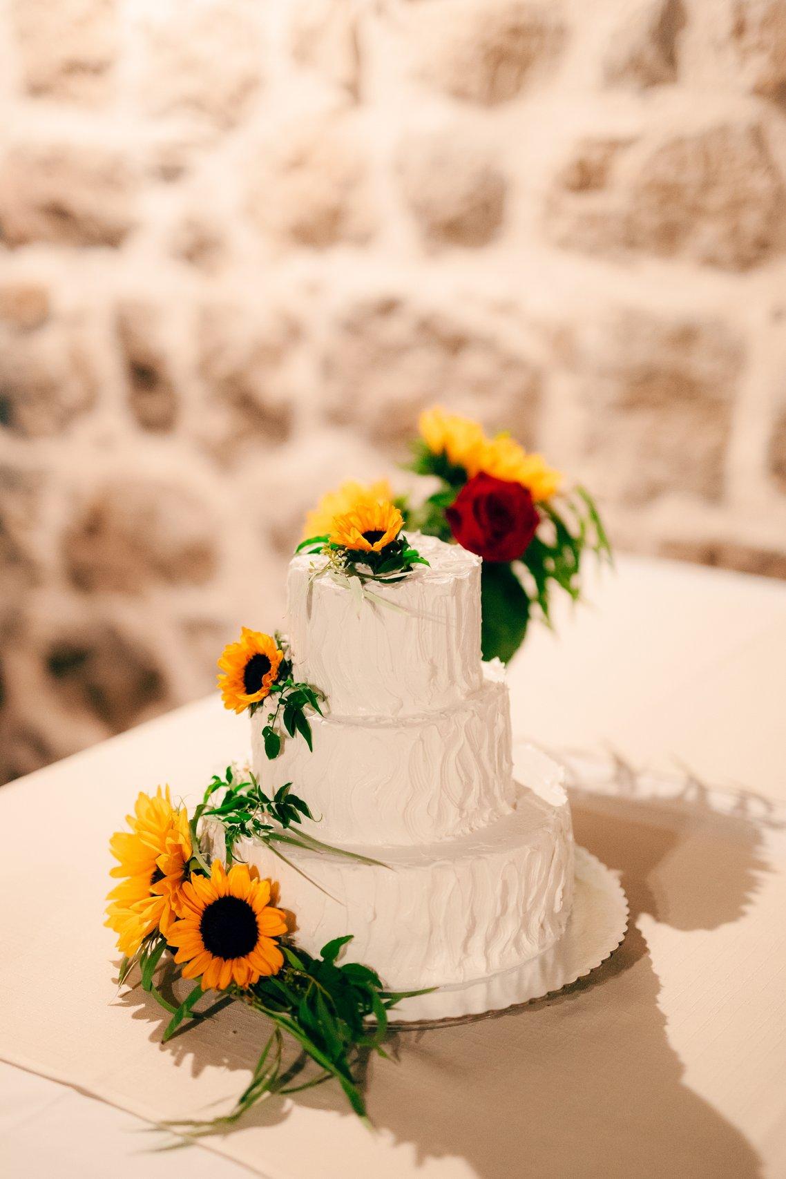 white buttercream wedding cake decorated with yellow sunflowers on each tier