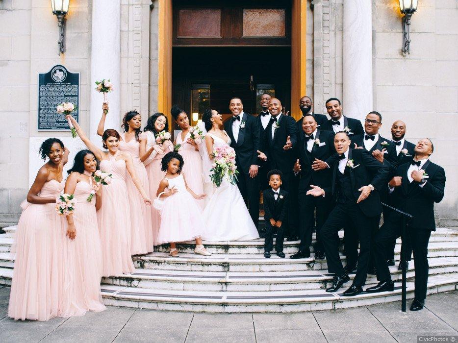 Wedding party photo op outside wedding venue with bride and groom at the center and both sides of wedding party on either side