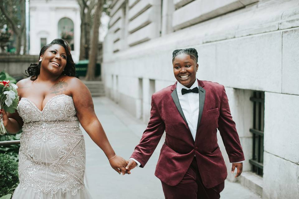 two brides walking down the street holding hands and smiling