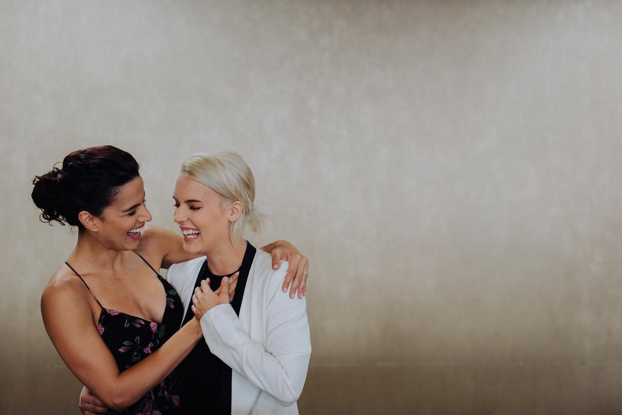 same-sex couple laughs in candid engagement photo