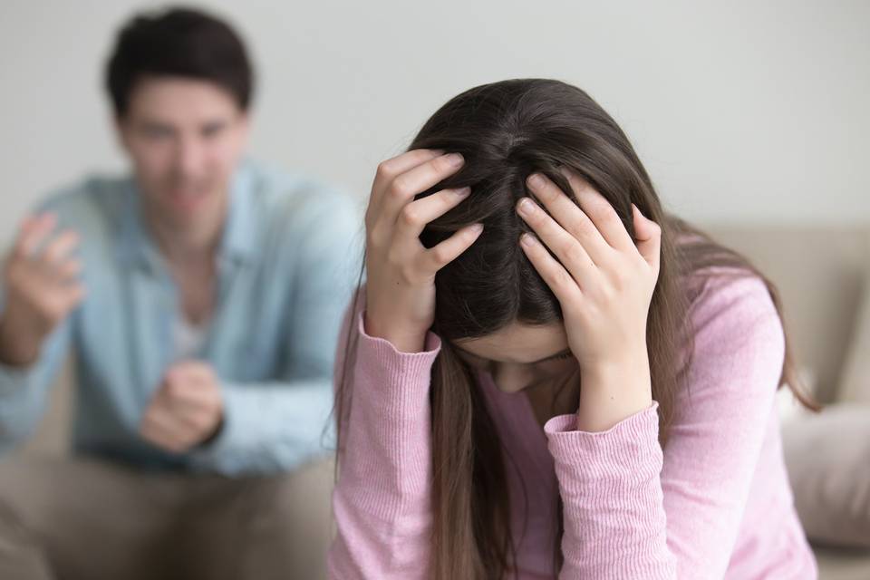 woman with head in hands as partner yells at her