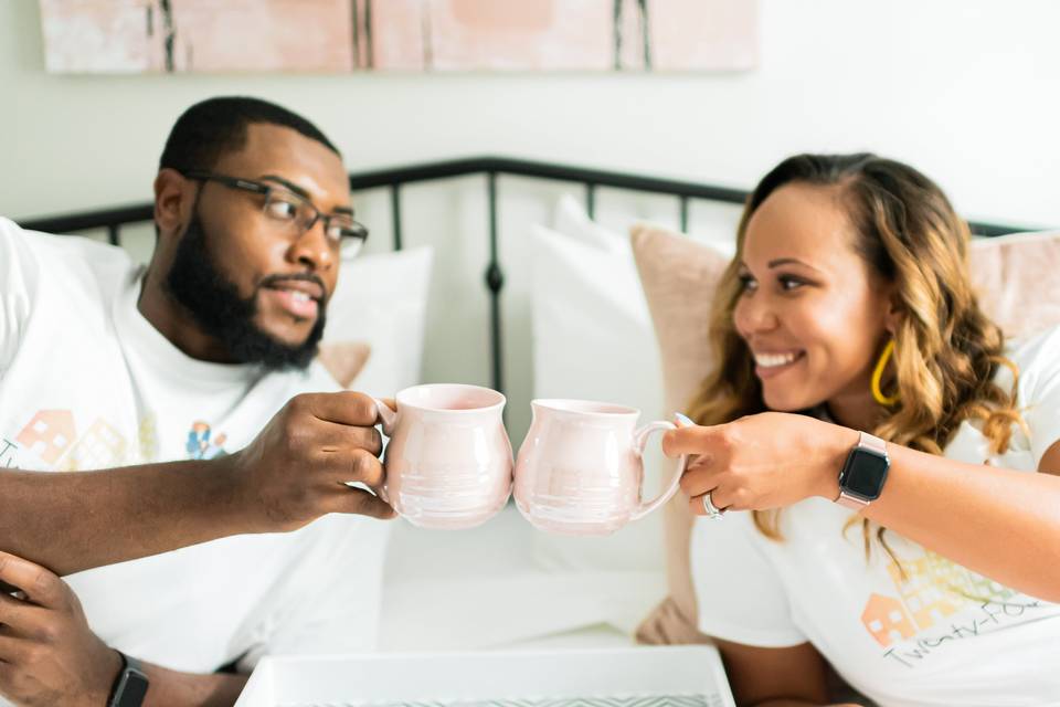 couple relaxing on bed with coffee mugs staycation at home