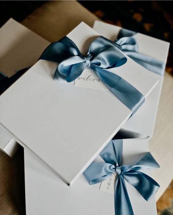 white wedding welcome boxes decorated with light blue satin bows