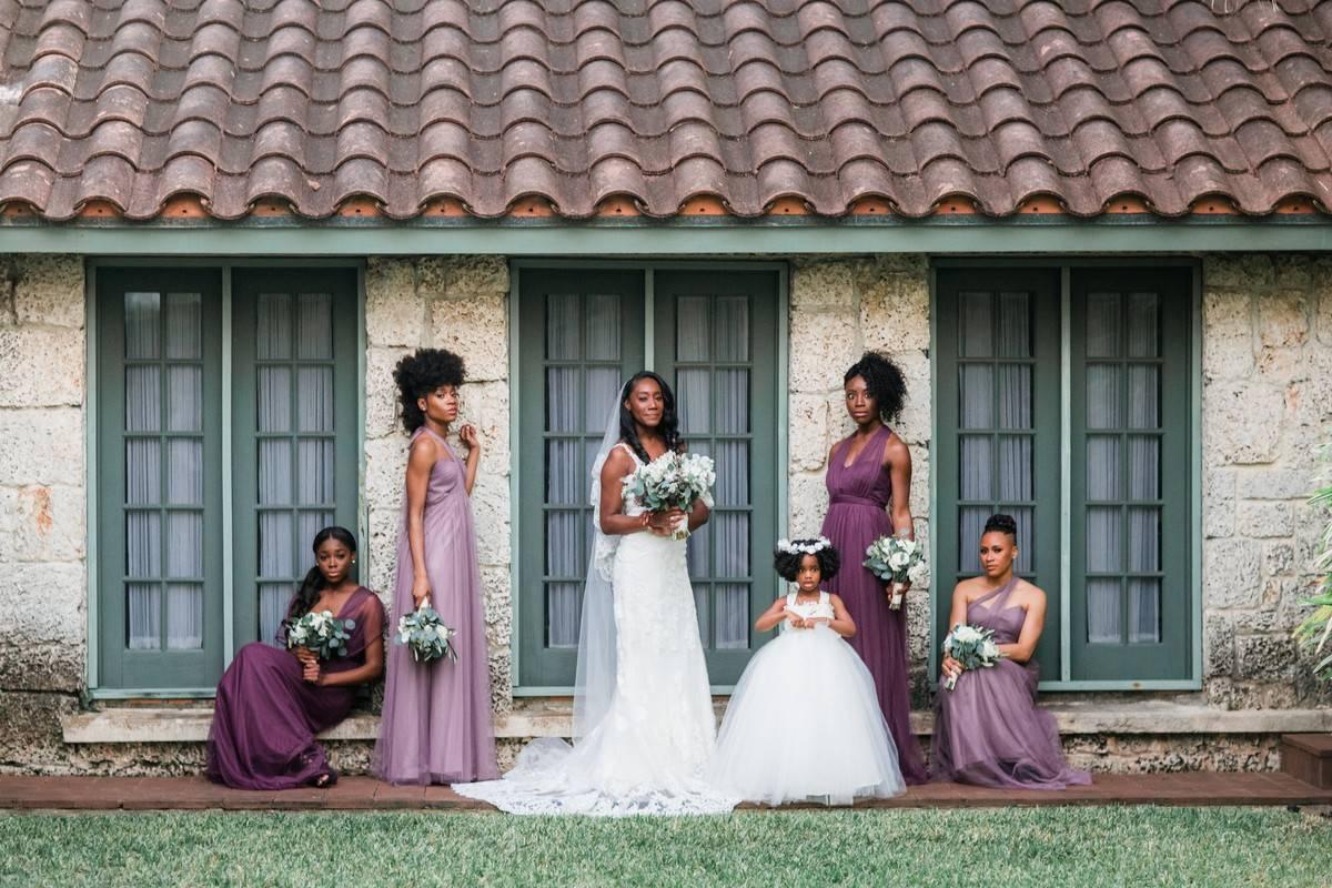 Photo of bride and her bridesmaids outside with bridesmaids in alternating shades of purple