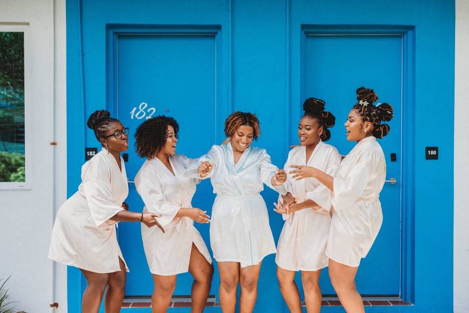 bride and bridesmaids wear matching white robes and dance