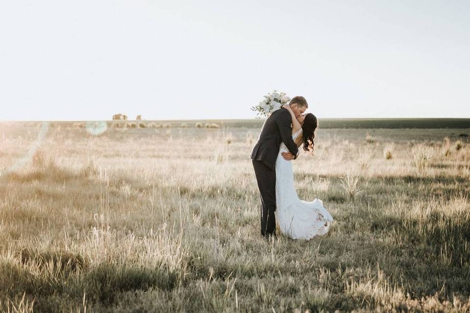 bride and groom kiss in open field