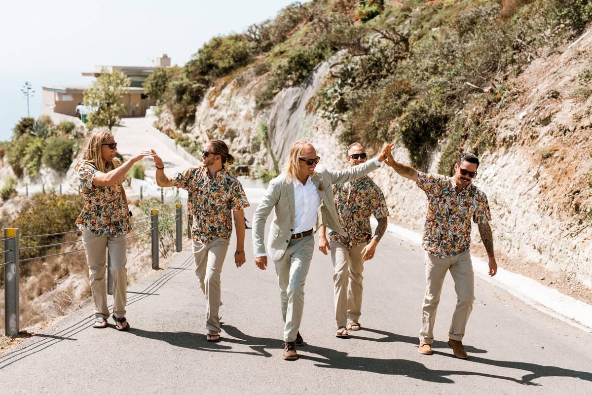 groom high-fives groomsman wearing hawaiian button-down shirt as they walk with the rest of the groomsmen