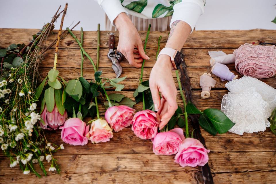 hands trimming pink roses on a table