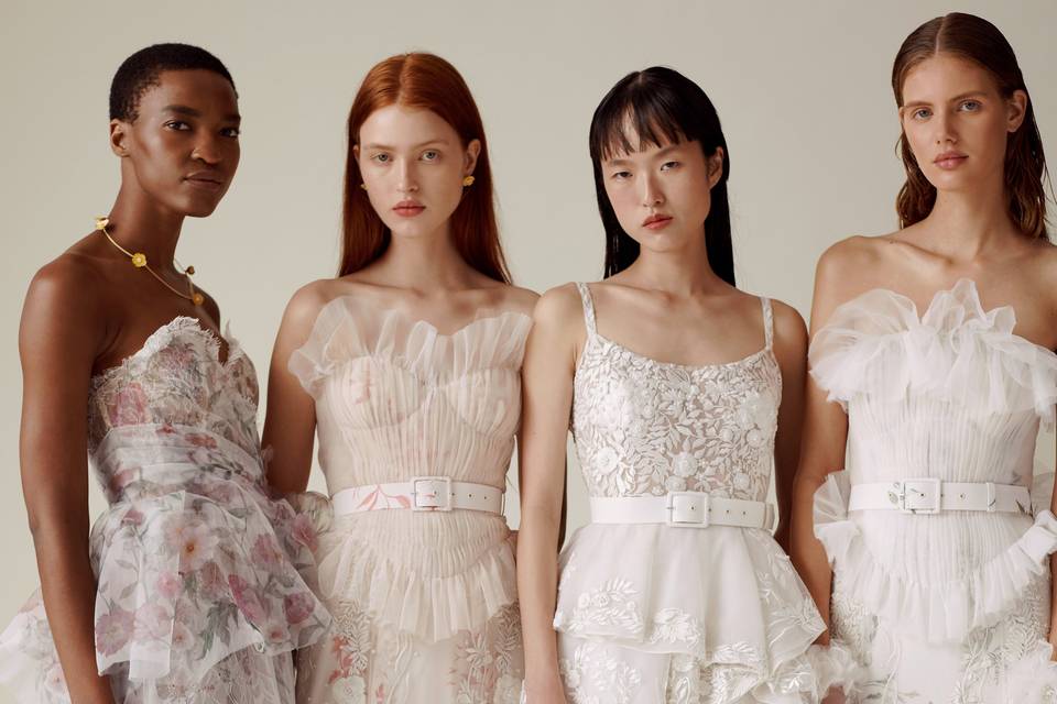 four models stand side by side looking at the camera wearing wedding dresses