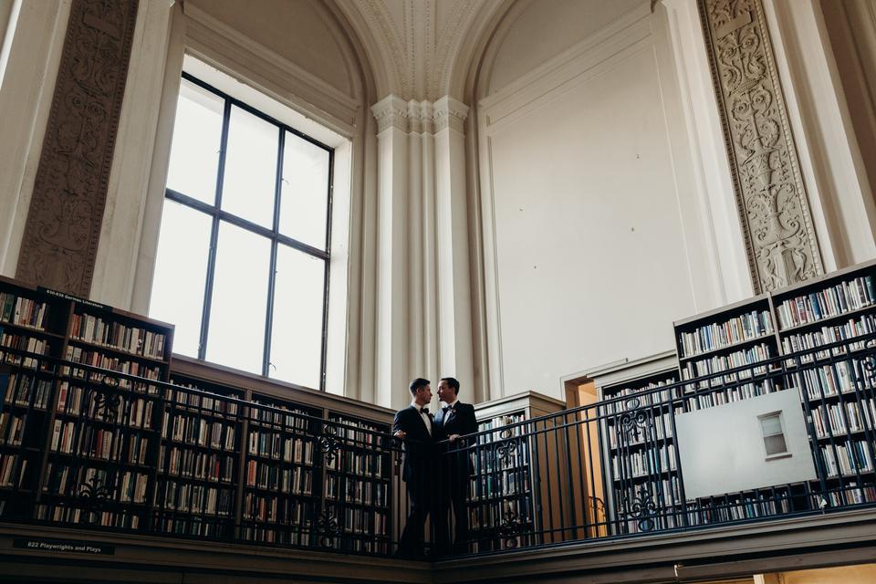 two grooms stand on balcony at parkway library in philidelphia
