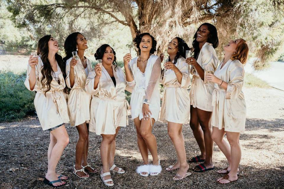 bride and bridesmaids wearing robes and toasting champagne