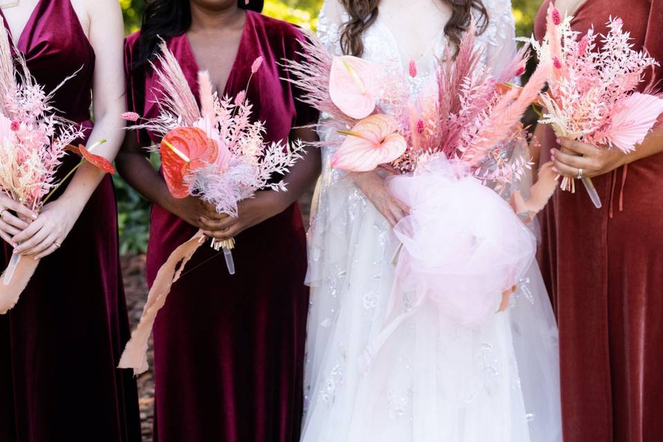 bride with her three bridesmaids holding modern tropical wedding bouquets with pink anthurium dyed pampas grass and bleached italian ruscus