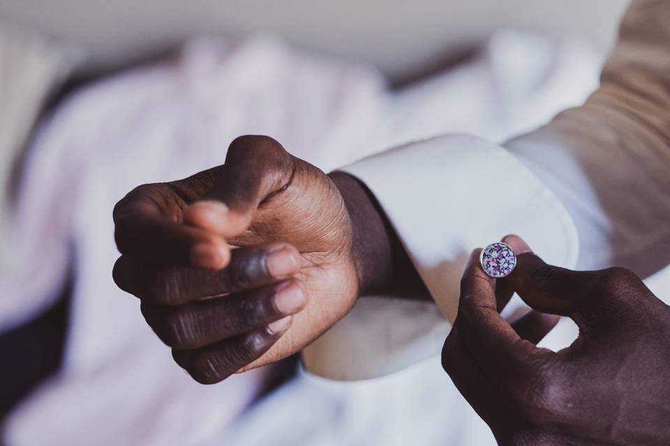 Man attaching a colorful cuff link to the cuff of his shirt