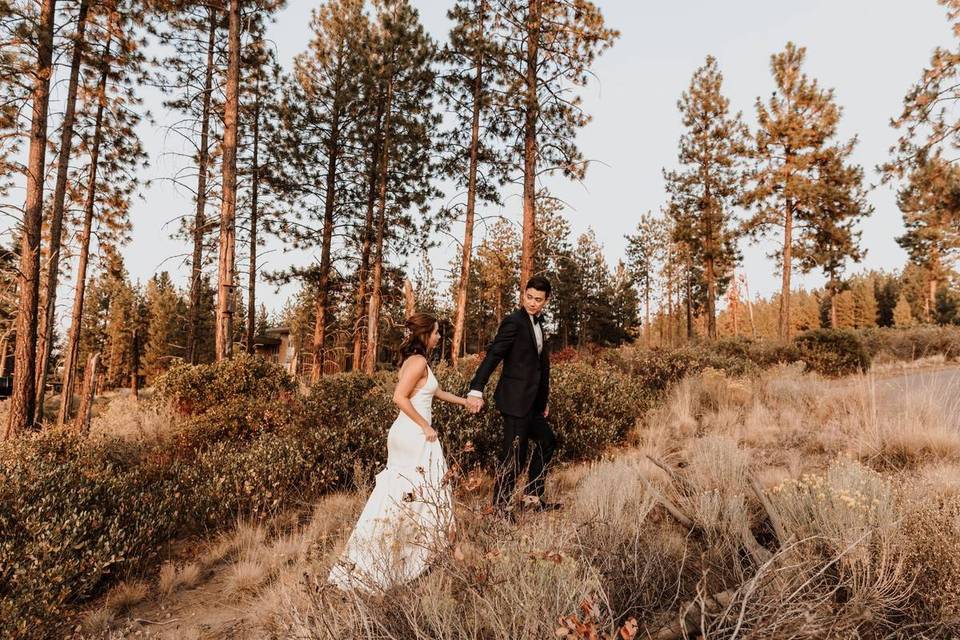 bride and groom walk up a hill while holding hands