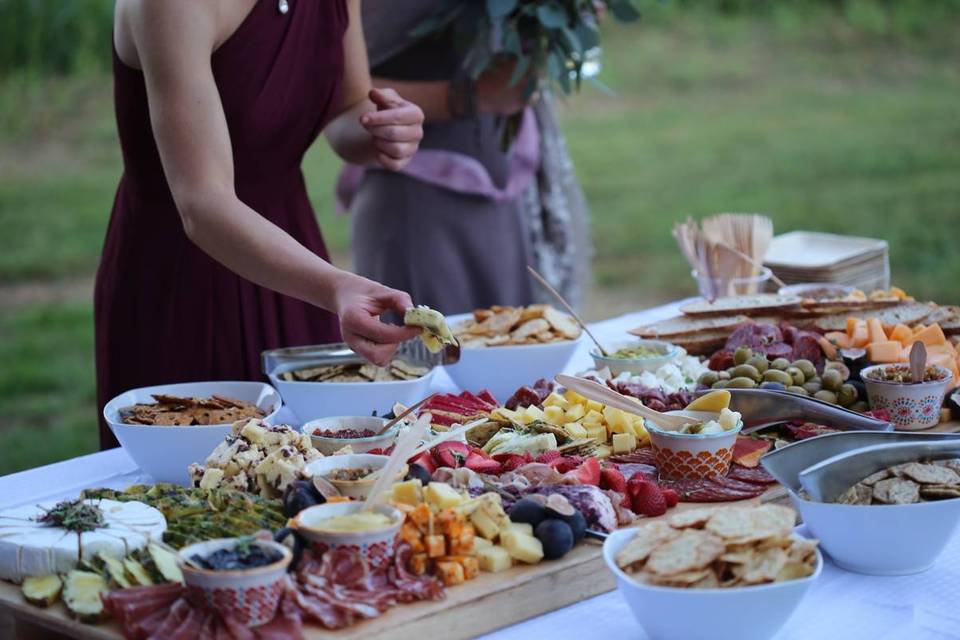 woman taking food from charcuterie board