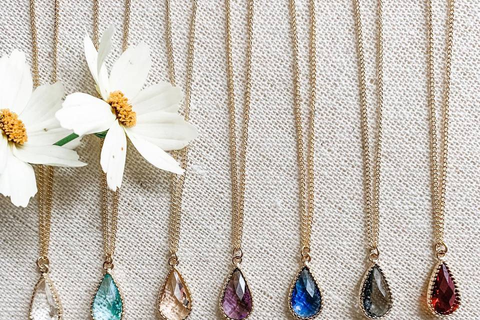 Seven teardrop gemstone bridesmaid necklaces with different color crystals on a gold chain
