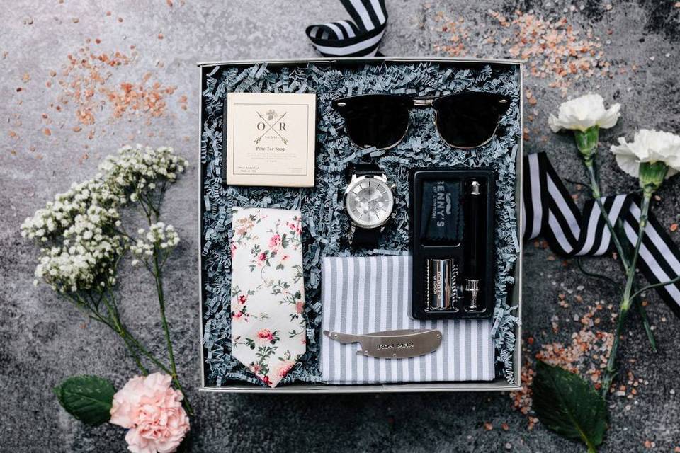 Groomsmen gift box with sunglasses, a watch, a floral tie, and other gifts