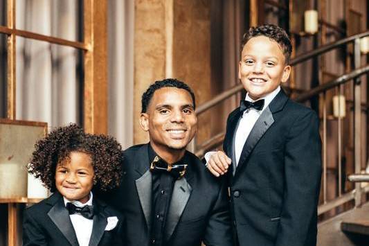 groom flanked by two ring bearers all wearing tuxedos