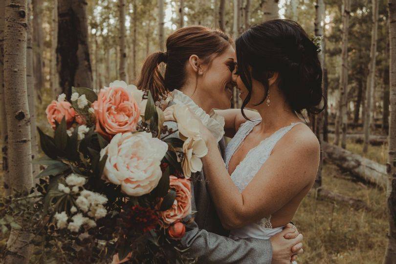 Couple kissing in nature with a bouquet of flowers