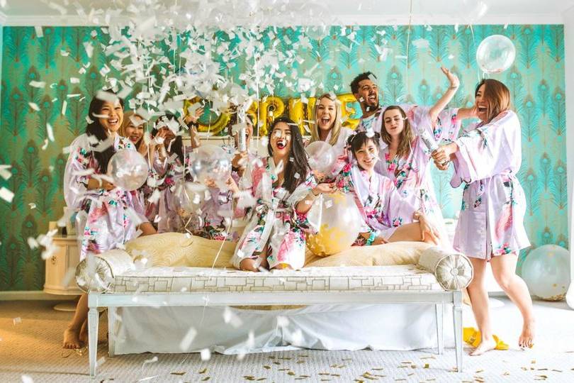 Bride and her bridal party celebrating in a hotel room decorated with balloons and confetti