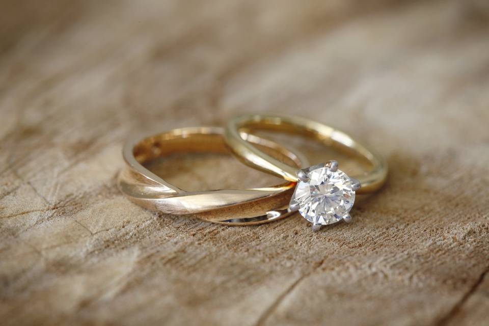 Solitaire engagement ring with plain gold band next to gold wedding band