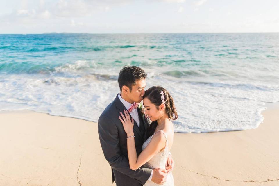 groom and bride kissing near the ocean
