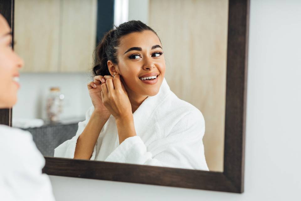 Woman in bathrobe putting on earrings