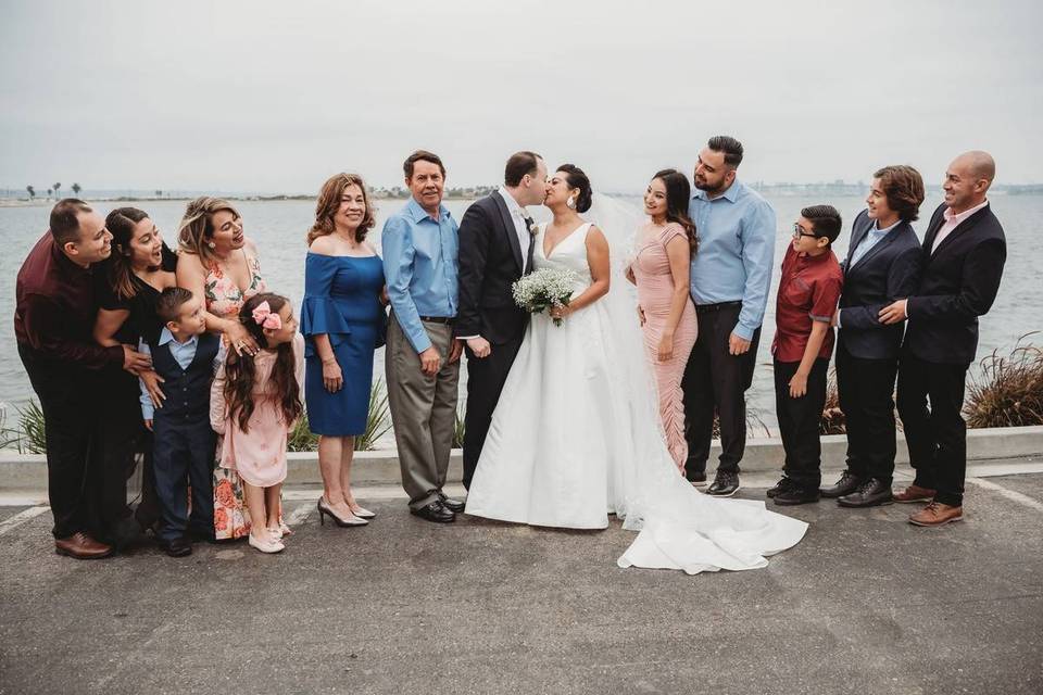 wedding couple kissing surrounded by happy family members