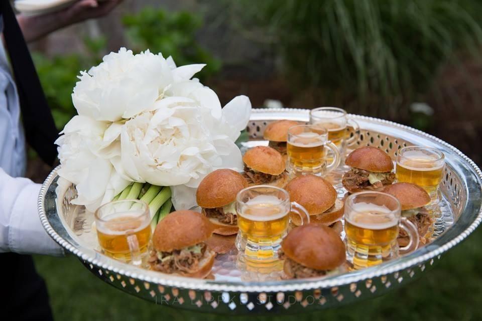 sliders and mini glasses of beer on a silver catering platter