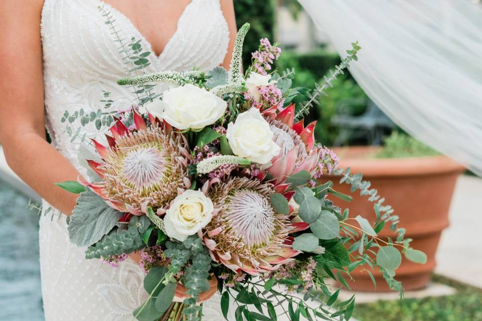 bride holding bouquet with two king proteas and eucalyptus