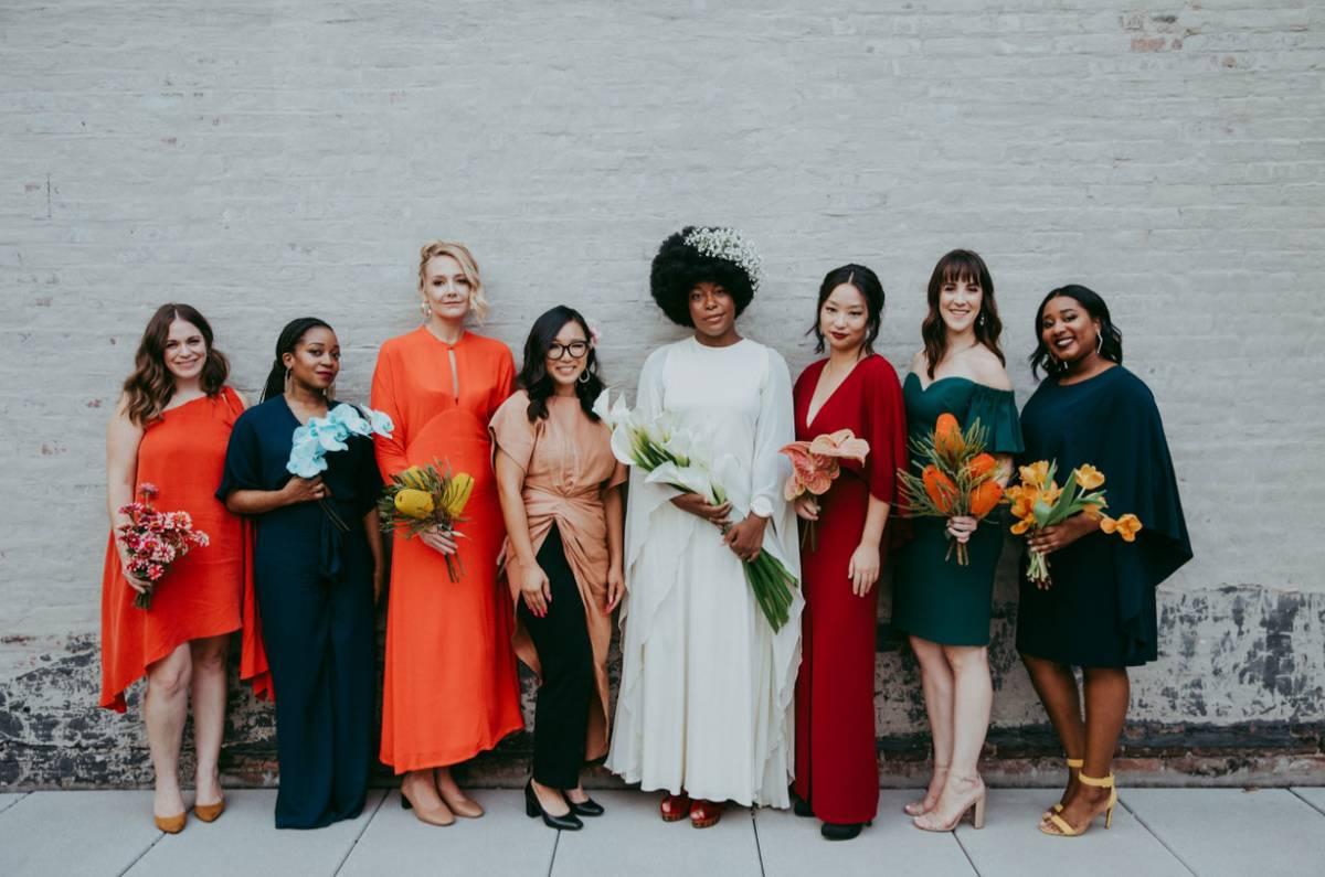 Bride wearing white posing with bridesmaids in alternating bright and dark hues