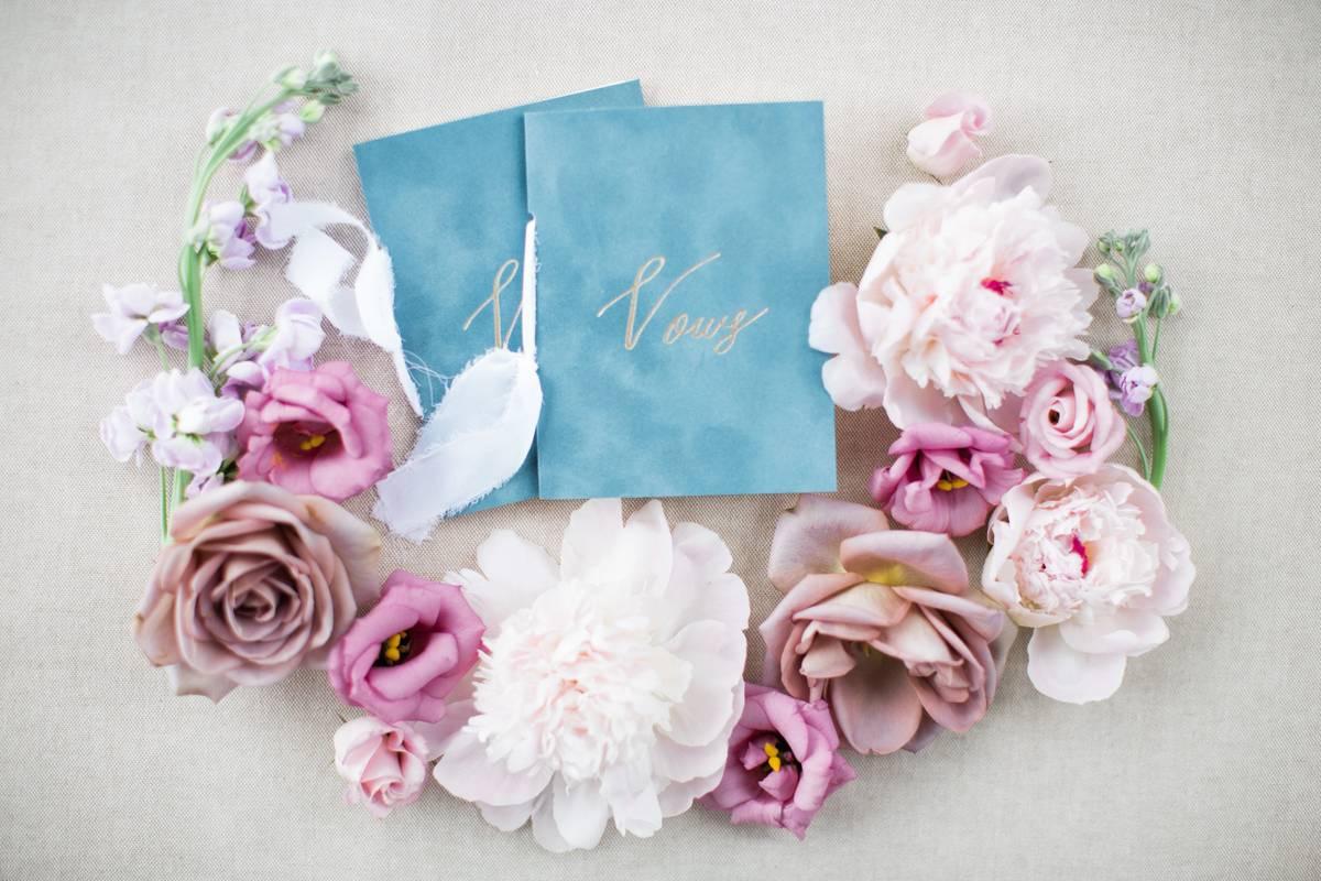 blue his and hers wedding vow books surrounded by pink roses