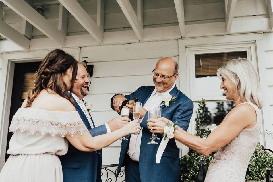 wedding couple and parents of the bride pouring champagne outdoors
