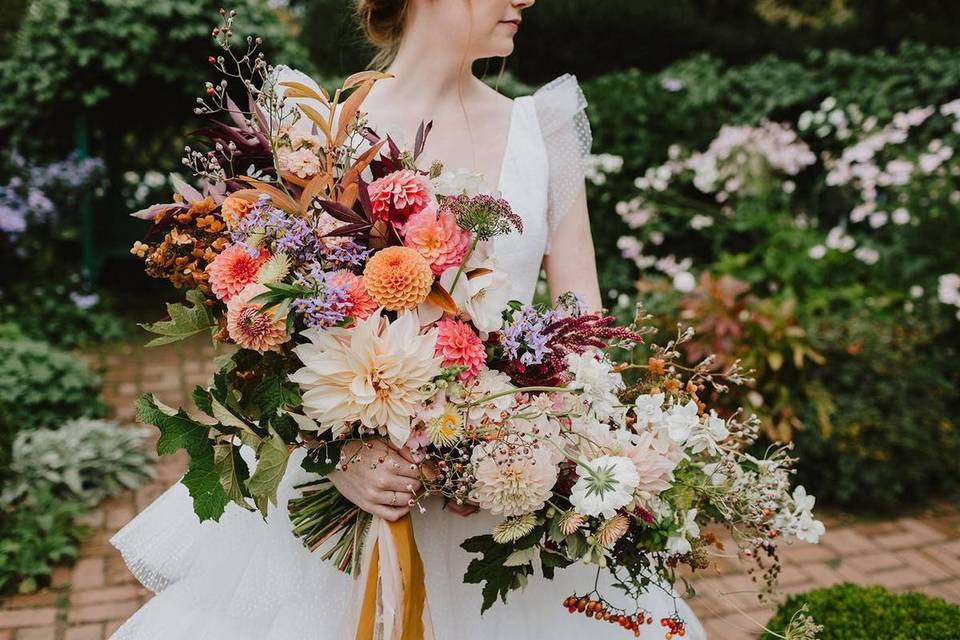 fall wedding bouquet with cafe au lait dahlias, orange pompom dahlias and abundant greenery