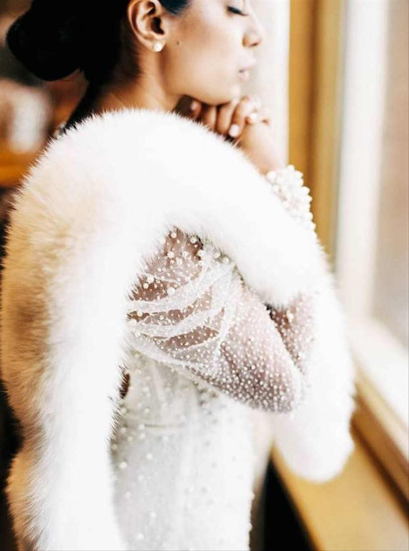 portrait of a bride wearing a beaded wedding dress and white fur shawl