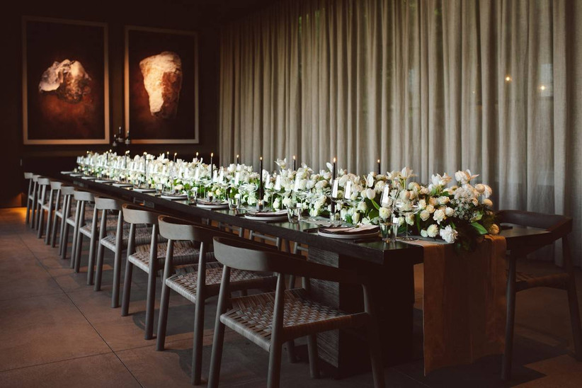 long wedding reception with white floral centerpieces and tall black taper candles down the center