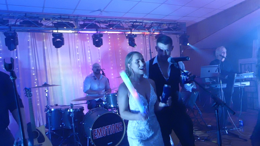 Bride + Groom singing on stage at their Wedding Celebration with ‘The Emotions'